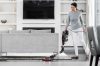 Woman in a grey sweater & white pants cleaning effortlessly under her sofa with a Shark HV390 Duo-clean TruePet